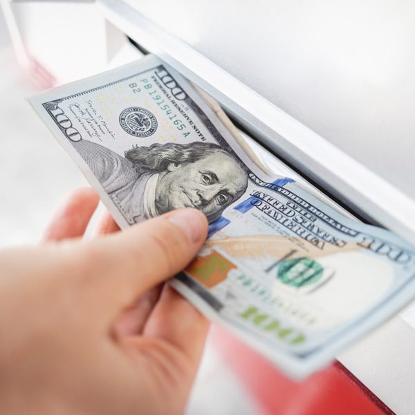 Hand pulling hundred-dollar bills from an ATM cash slot