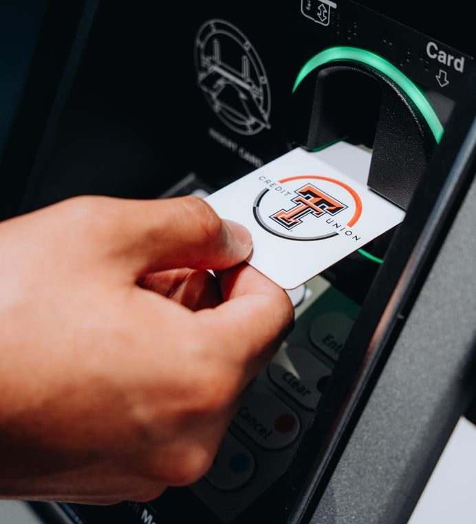 A Texas Tech Credit Union debit card being inserted into an ATM