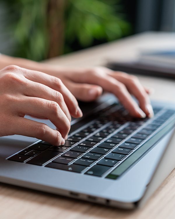 Hands typing on a laptop keyboard