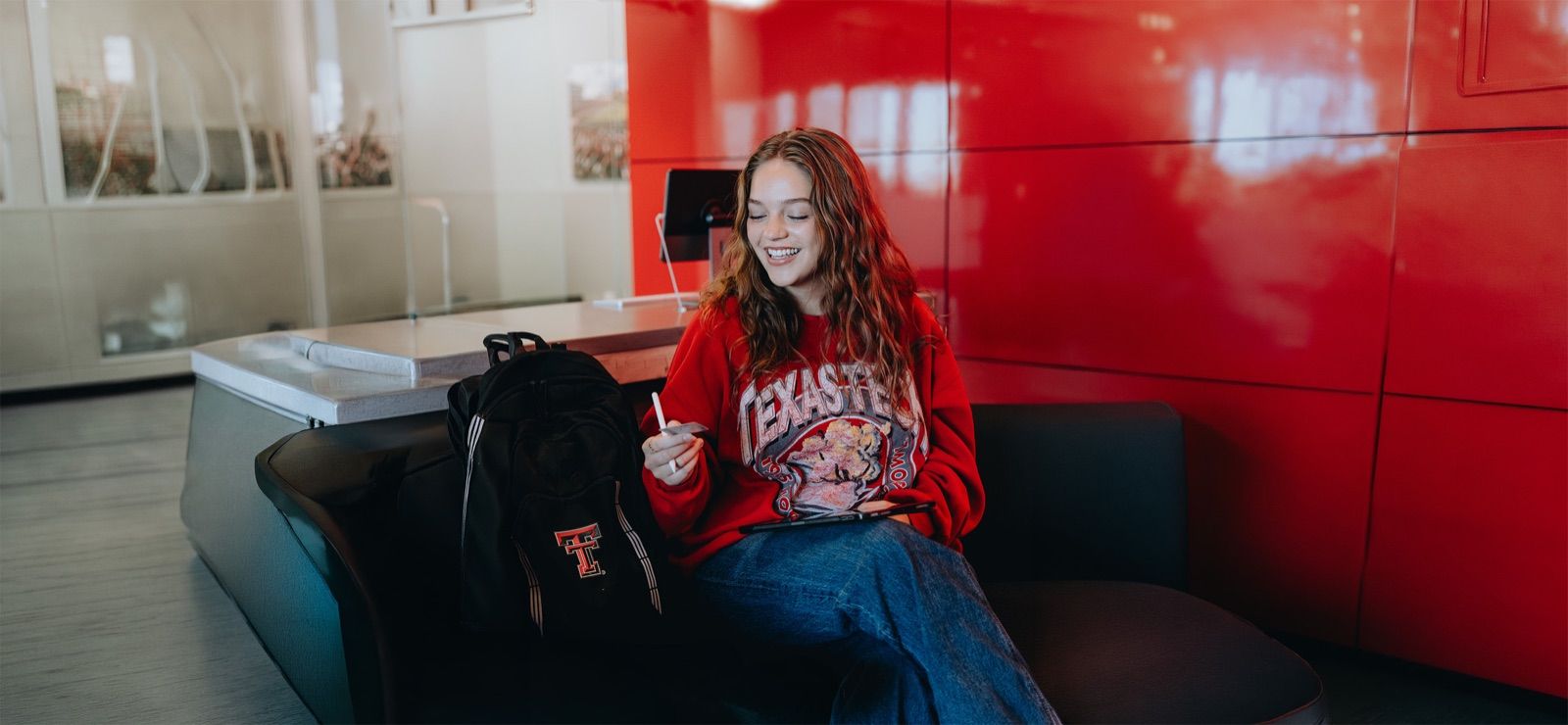 Student in a Texas Tech sweatshirt using mobile banking