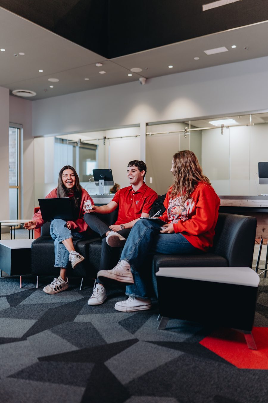Members relaxing on a couch with laptops in a Texas Tech Credit Union branch