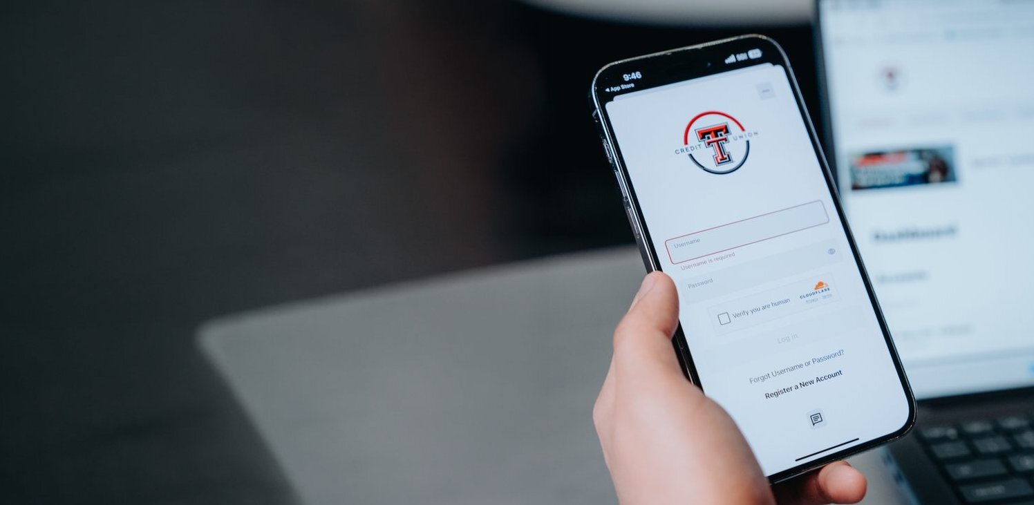 Hand holding a phone with the Texas Tech Credit Union mobile banking app open