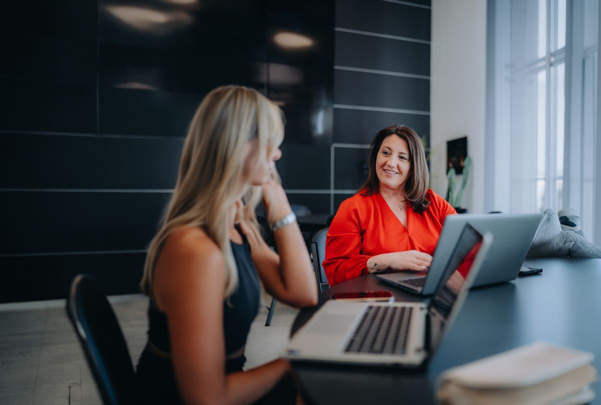 Two people reviewing finances on laptops
